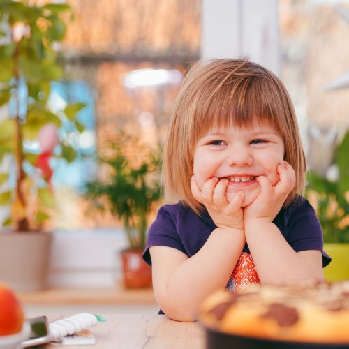 Happy child sitting at a table ready to eat